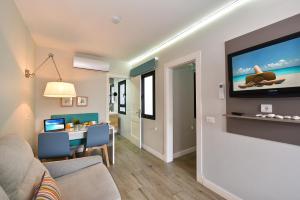 a living room with a couch and a tv on a wall at Hotel Apartamento Bajamar in Las Palmas de Gran Canaria