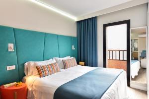 a bedroom with a large bed with a blue wall at Hotel Apartamento Bajamar in Las Palmas de Gran Canaria