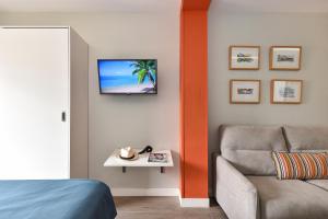 a room with a couch and a tv on the wall at Hotel Apartamento Bajamar in Las Palmas de Gran Canaria