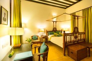 a bedroom with a bed and a desk and a bed sidx sidx sidx at Maison Perumal Pondicherry - CGH Earth in Puducherry