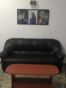 a black leather couch in a living room with pictures on the wall at Villa Fiorita in Dickwella