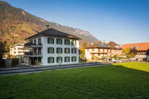 a white building with a black roof on a green field at Dependance First in Interlaken