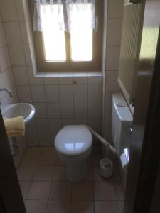 a bathroom with a toilet and a sink and a window at Knüllhotel Tann-Eck in Knüllwald
