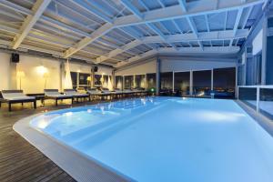 a pool in a hotel with tables and chairs at Hotel Horizon in Montegranaro
