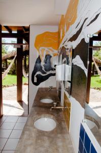 Baño con 3 lavabos y una pintura en la pared en Jangada Lodge, en São Miguel do Gostoso