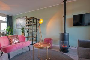 salon z różową kanapą i kominkiem w obiekcie Amsterdam Beach Apartment 90 w Zandvoort