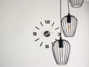 um relógio e dois lustres numa parede branca em Apartment Amber, Kranjska Gora - Center em Kranjska Gora