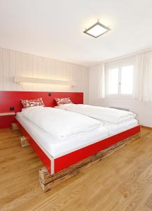 Schlafzimmer mit einem großen Bett mit einem roten Kopfteil in der Unterkunft Alpinhotel Bort in Grindelwald