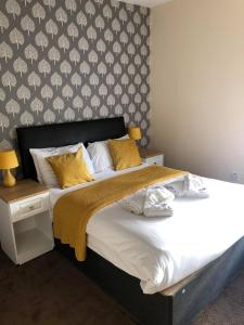 ein Schlafzimmer mit einem großen Bett mit gelben Kissen in der Unterkunft Minworth Lodge in Minworth