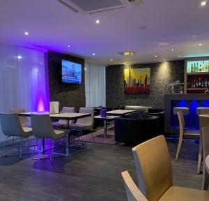 a restaurant with tables and chairs and a tv on the wall at Mercure Strasbourg Aéroport in Ostwald