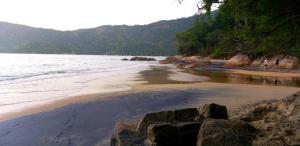 a beach with people walking on the sand and water at Suíte da Vila - Beira Mar in Abraão