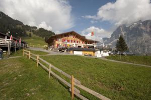 a wooden building on a hill with a fence at Alpinhotel Bort in Grindelwald