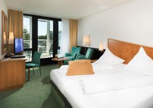 バート・メルゲントハイムにあるベスト ウエスタン プレミア パークホテル バート メルゲントハイムのベッド、デスク、椅子が備わるホテルルームです。