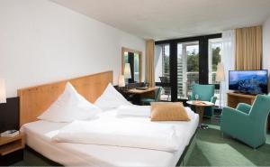 Habitación de hotel con cama, escritorio y sillas en Best Western Premier Parkhotel Bad Mergentheim, en Bad Mergentheim