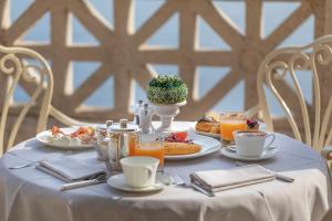 a table with a white table cloth with food and orange juice at Bellevue Syrene in Sorrento