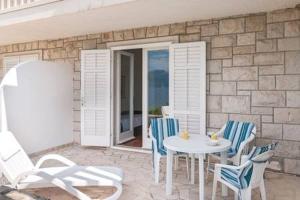 a patio with a white table and chairs and a stone wall at Beach Apartment Viktor 2 in Postira