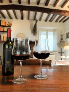 dos copas de vino tinto en una mesa de madera en Casa Nonna Rosa en Valpromaro
