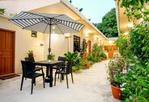 a table and chairs with an umbrella in a courtyard at Paguro Villa in Ukulhas