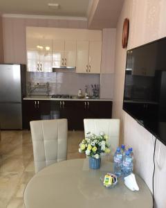MG Apartments in Tbilisi في تبليسي: مطبخ مع طاولة مع الزهور وزجاجات الماء