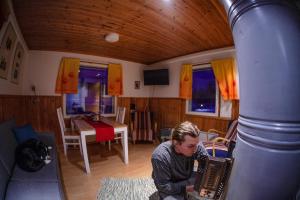 Ein Mann, der im Wohnzimmer Akkordeon spielt. in der Unterkunft Lohi-Aslakin Lomamökit in Utsjoki