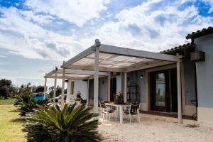 a pergola on a house with a table and chairs at Punta del Cane in Fontane Bianche