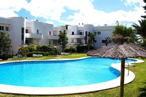 een groot zwembad met een parasol en een gebouw bij Apartamento Estepona Golf in Estepona