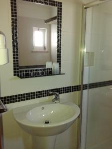 a bathroom with a sink and a mirror and a shower at Alojamentos Vitinho - Vila Nova Milfontes in Vila Nova de Milfontes