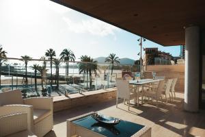 een patio met een tafel en stoelen en uitzicht op de oceaan bij GRAND TERRACE APARTMENT in Puerto de Alcudia in Alcudia