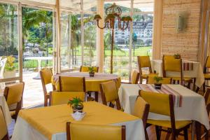 a restaurant with tables and chairs and a large window at Casa do Sol Hotel in Petrópolis