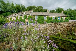 a stone house with flowers in front of it at The Swan Hotel in Bibury