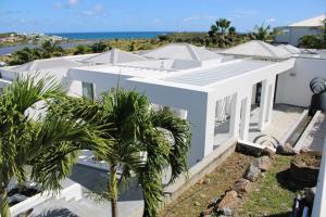 ein weißes Haus mit Palmen davor in der Unterkunft The Pearl in Orient Bay