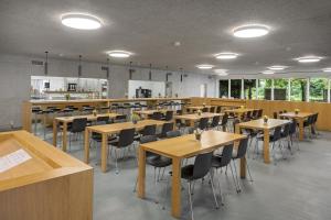 ein Restaurant mit Holztischen und -stühlen in einem Zimmer in der Unterkunft Lausanne Youth Hostel Jeunotel in Lausanne