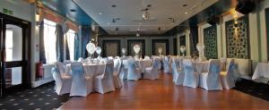 a row of tables and chairs in a room at Fairway Hotel in Bathgate