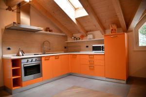 een keuken met oranje kasten en een raam bij Chalet Villa Bianca in Tesero