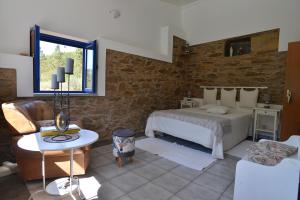 a bedroom with a bed and a stone wall at REFÚGIO DO RAPOSO/CASA DA RIBEIRA (AGROTURISMO) in Proença-a-Nova