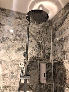 a shower with a shower head and a stool in a bathroom at Eclipse Apartment No 2 in Newmarket