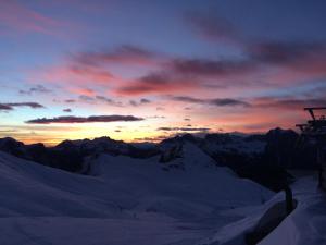 een zonsondergang boven een met sneeuw bedekte berg bij Majon del Tisler in Canazei