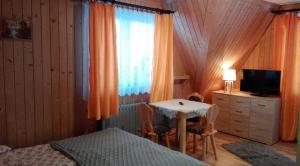 a bedroom with a table and a bed and a television at Pokoje Goscinne U Janki in Murzasichle
