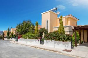 una casa con arbustos y árboles frente a una calle en Latchi Marina View, en Neo Chorio