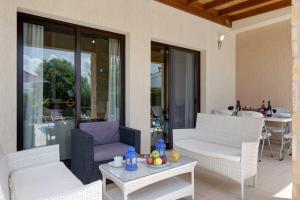 eine Terrasse mit weißen Möbeln und einem Tisch mit Obst darauf in der Unterkunft Villa Pashiana in Polis Chrysochous