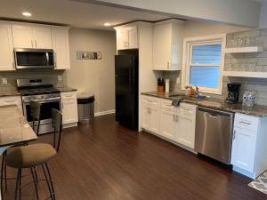 a kitchen with white cabinets and a black refrigerator at The Orange Door-Sleeps 10 in Louisville +13 photos