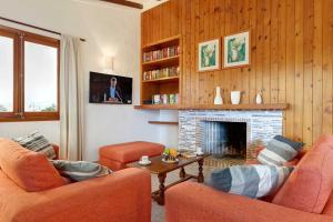 ein Wohnzimmer mit 2 orangenen Stühlen und einem Kamin in der Unterkunft Villa Animeta in Pollença