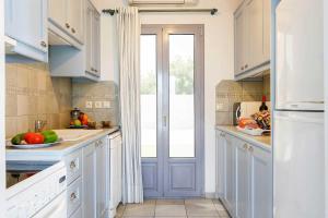 una cocina con armarios azules y una ventana en Villa Votsalo, en Kaligata