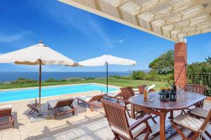 une terrasse avec une table, des chaises et une piscine dans l'établissement Villa Agnandi, à Lakíthra