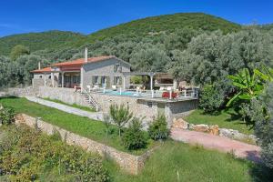 een stenen huis met een zwembad voor een berg bij Villa Leda in Sivota