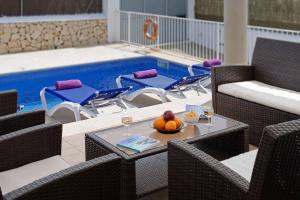 una piscina con sillas y una mesa con un bol de fruta en Villa Sagitaro, en Cala d´Or