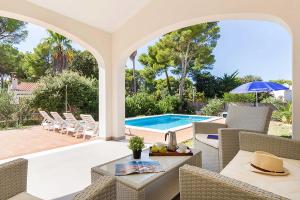 Un patio con mesa y sillas y una piscina. en Villa Son Gaieta, en Cala Galdana