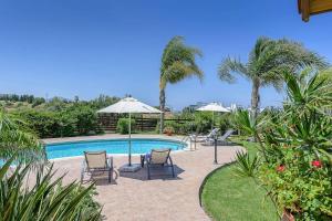 una piscina con dos sillas y sombrillas en Villa Yialos, en Neo Chorio