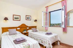 two beds in a room with a window at Villa Marcolis Mar in Cala Galdana +18 photos