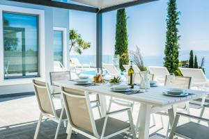 a white dining room table with white chairs and windows at Villa Della Luna in Vlachata